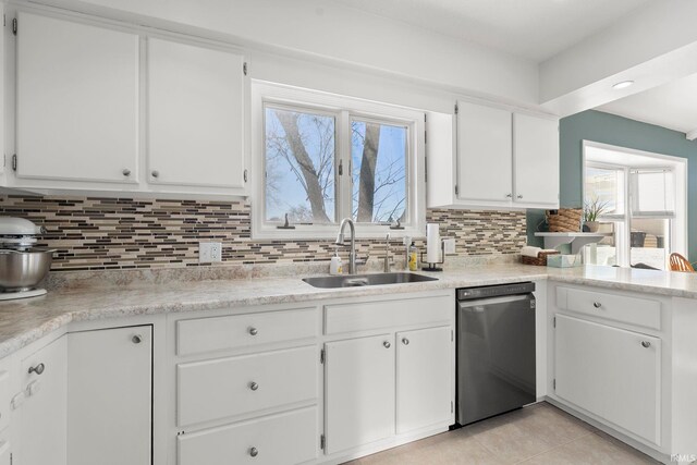 kitchen featuring dishwasher, light countertops, a sink, and white cabinetry