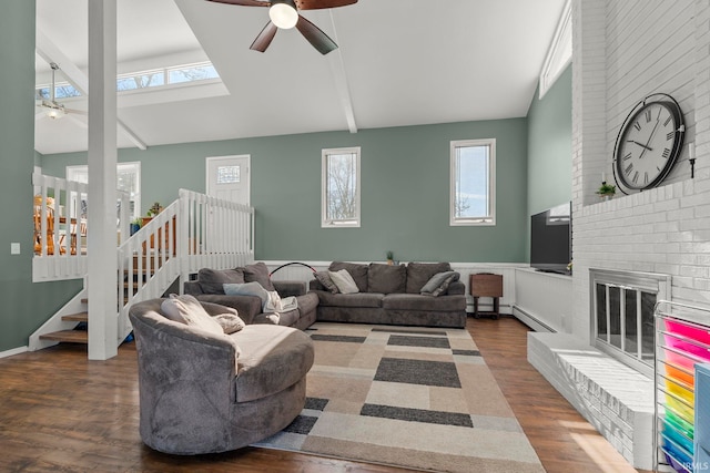 living area with stairs, a ceiling fan, a brick fireplace, and wood finished floors