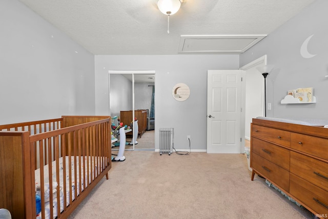 bedroom featuring light carpet, baseboards, radiator, a textured ceiling, and a closet