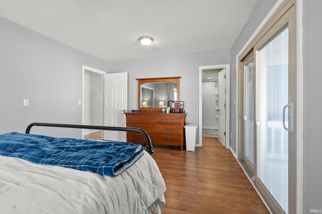 bedroom featuring a textured ceiling, a baseboard heating unit, and dark wood finished floors