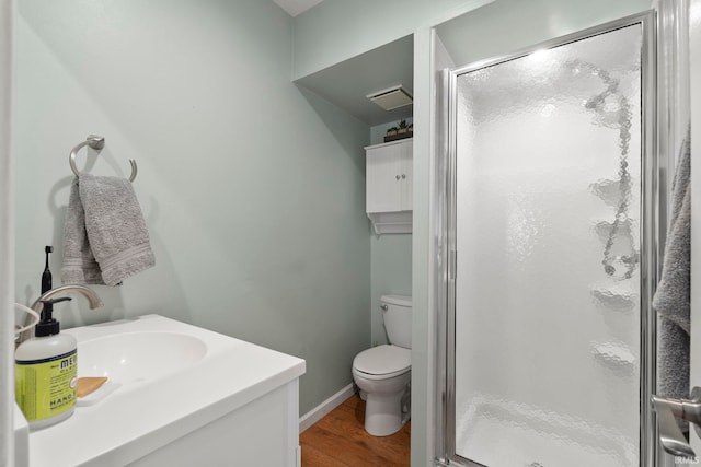 bathroom with a stall shower, baseboards, toilet, wood finished floors, and vanity