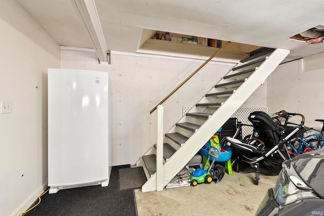 finished basement with stairs and freestanding refrigerator