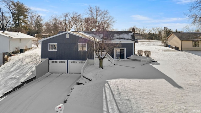 snow covered property featuring a garage and stairway