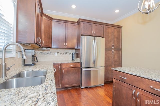 kitchen with dark wood-type flooring, a sink, ornamental molding, freestanding refrigerator, and tasteful backsplash