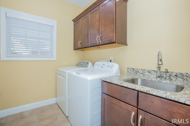 washroom featuring cabinet space, washing machine and dryer, baseboards, and a sink