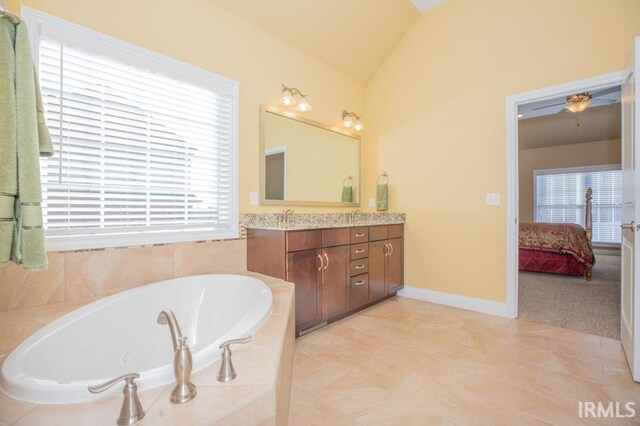 ensuite bathroom featuring lofted ceiling, ensuite bath, tile patterned flooring, vanity, and a bath