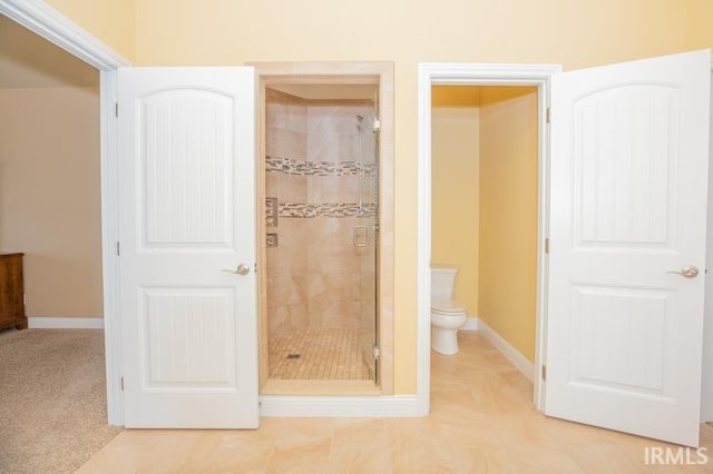 bathroom with a stall shower, baseboards, toilet, and tile patterned floors