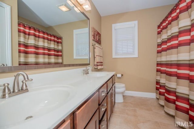 bathroom featuring baseboards, a sink, toilet, and double vanity