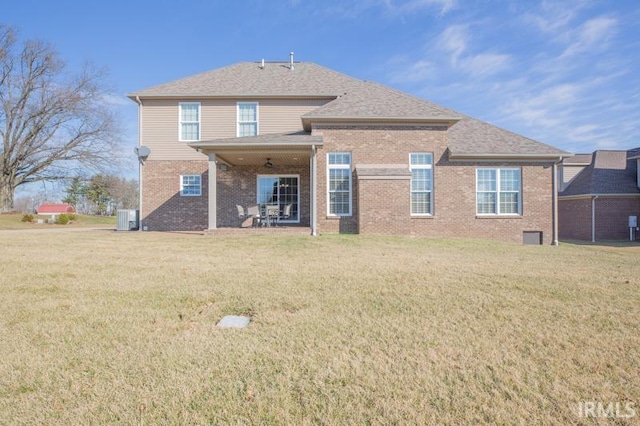 rear view of house with a yard, central AC unit, and brick siding