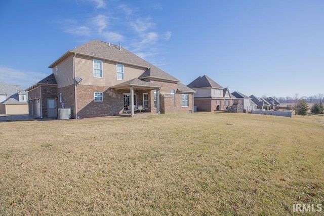 rear view of house featuring brick siding, a lawn, an attached garage, and central air condition unit