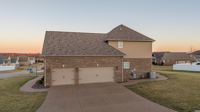 traditional-style house with driveway, a garage, a front lawn, central AC, and brick siding