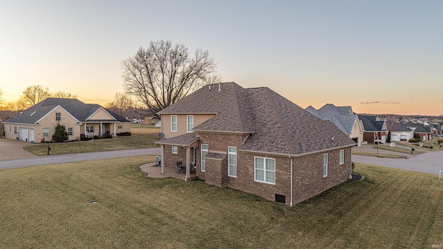 traditional-style home with a yard, a shingled roof, a residential view, and brick siding