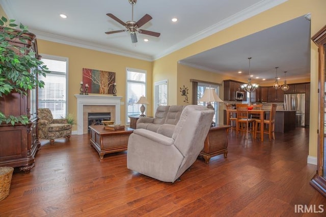 living area featuring a tiled fireplace, ornamental molding, dark wood-type flooring, and a wealth of natural light