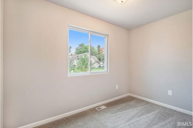 spare room featuring carpet, visible vents, and baseboards