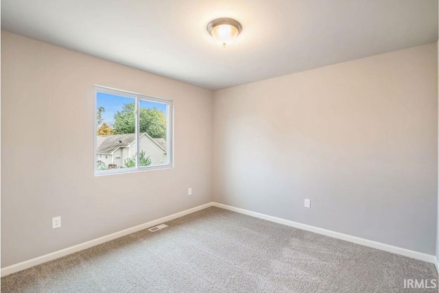 empty room with carpet, visible vents, and baseboards