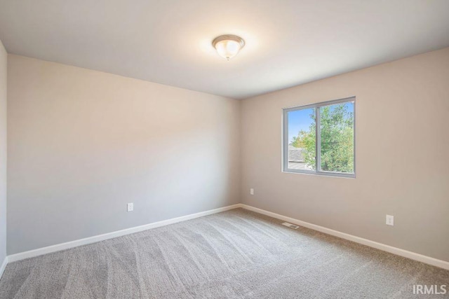 spare room featuring carpet, visible vents, and baseboards