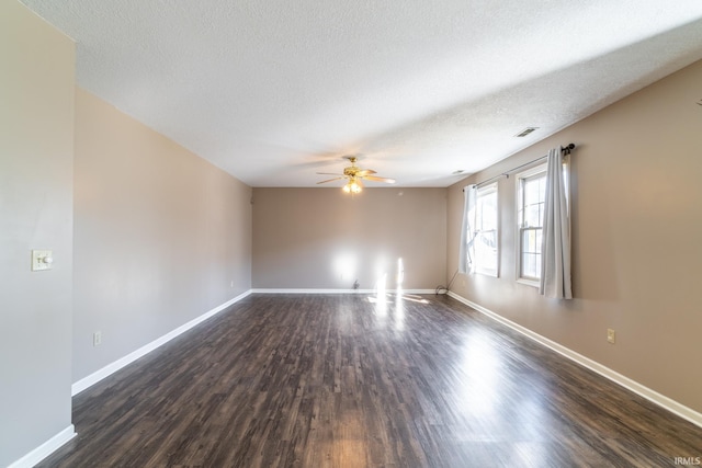 spare room featuring baseboards, visible vents, dark wood finished floors, ceiling fan, and a textured ceiling