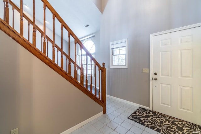 foyer entrance with light tile patterned floors, stairway, visible vents, and baseboards