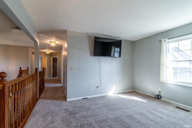 carpeted spare room featuring visible vents and baseboards