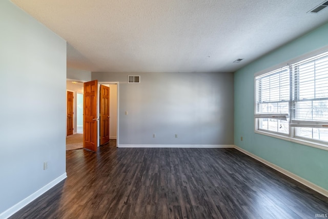 empty room with baseboards, visible vents, and dark wood-style flooring