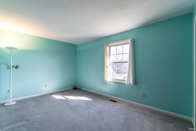 carpeted spare room featuring a textured ceiling, visible vents, and baseboards