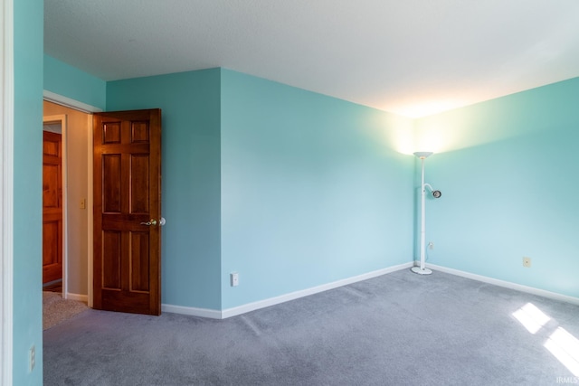 spare room featuring baseboards and carpet flooring