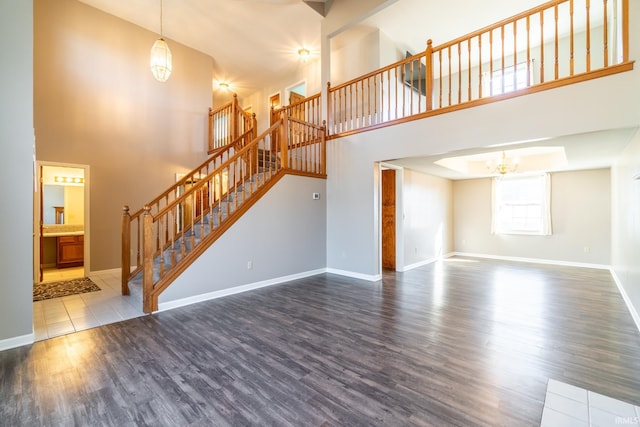 unfurnished living room with stairs, baseboards, a chandelier, and dark wood-type flooring