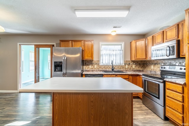 kitchen featuring appliances with stainless steel finishes, light countertops, a sink, and a center island