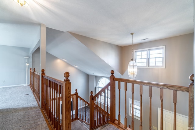 staircase with carpet flooring, visible vents, baseboards, and an inviting chandelier