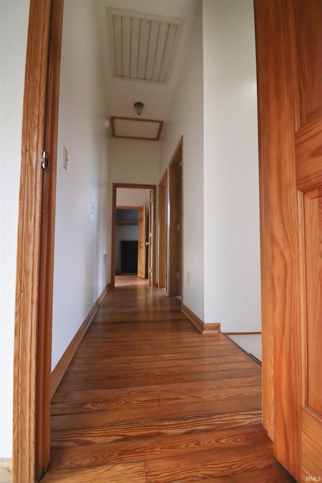 hallway featuring wood finished floors, visible vents, and baseboards