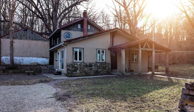 view of front of property with stone siding, a chimney, and stucco siding