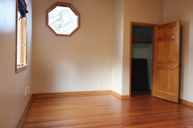 spare room with baseboards and wood finished floors