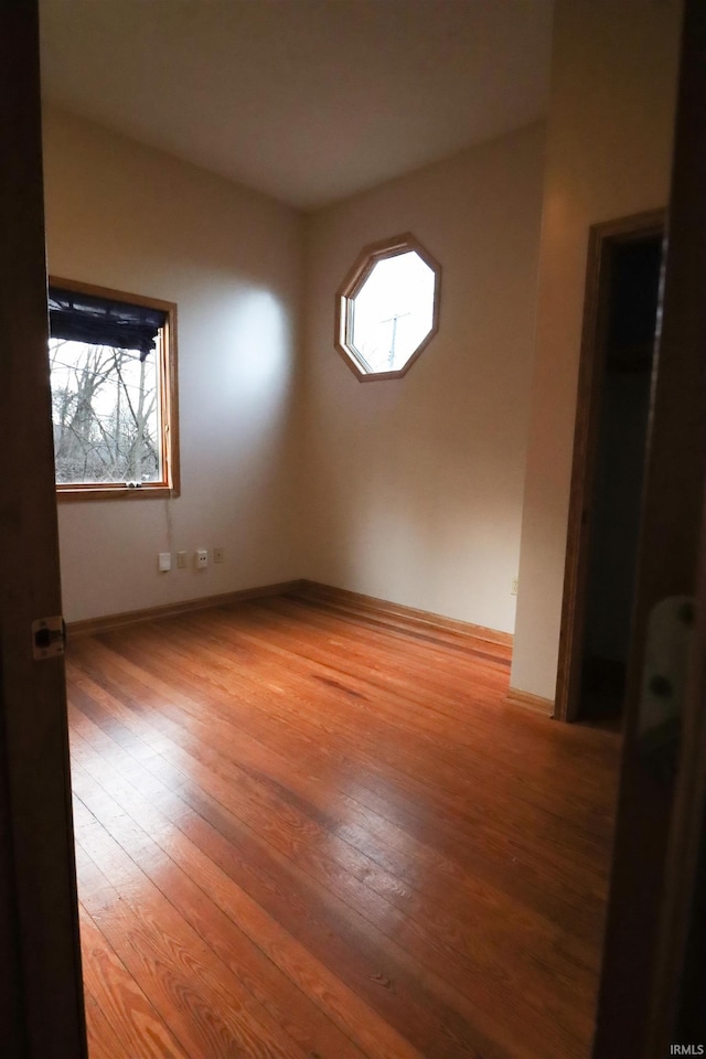 empty room with baseboards and hardwood / wood-style flooring