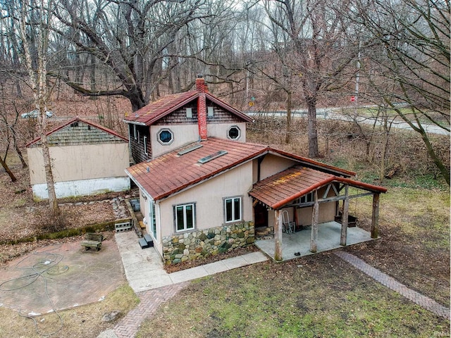 view of front of property with a tiled roof, a chimney, stone siding, and stucco siding