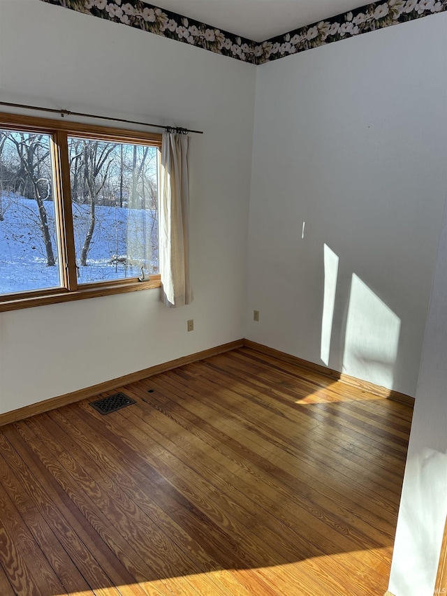 unfurnished room featuring hardwood / wood-style flooring, baseboards, and visible vents