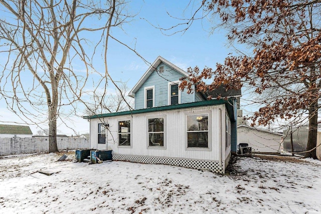 snow covered rear of property featuring fence