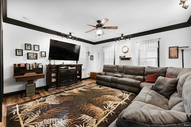 living room featuring baseboards, ceiling fan, ornamental molding, wood finished floors, and a fireplace