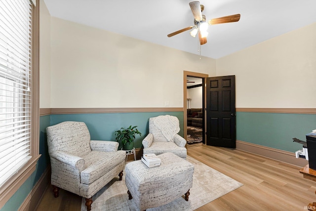 sitting room with ceiling fan, light wood finished floors, and baseboards