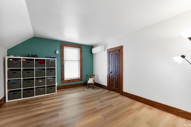 additional living space featuring lofted ceiling, a wall unit AC, baseboards, and wood finished floors