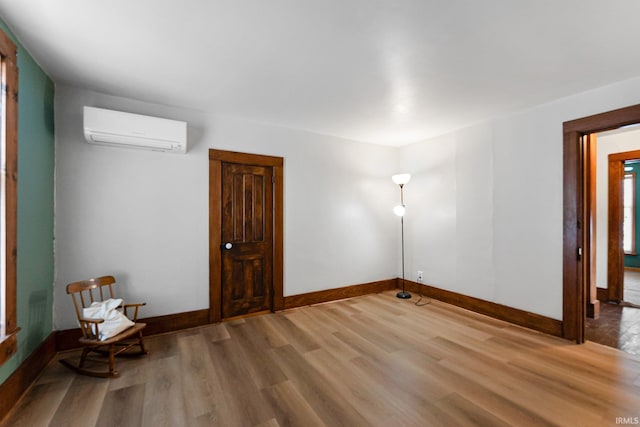 interior space featuring an AC wall unit, wood finished floors, and baseboards