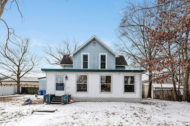 snow covered house featuring fence and entry steps