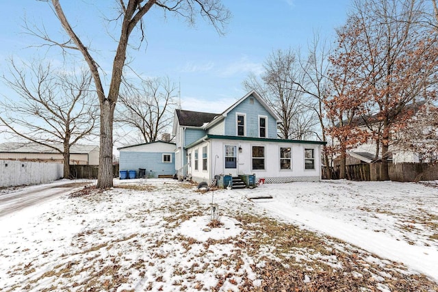 snow covered rear of property with entry steps and fence