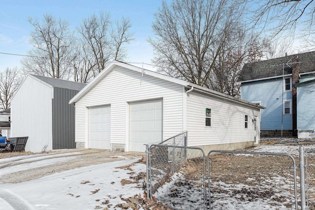 snow covered garage with a garage and fence