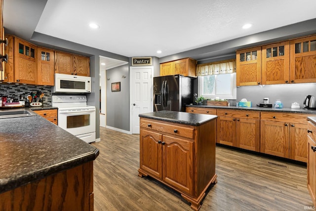 kitchen with white appliances, brown cabinetry, a sink, and a center island