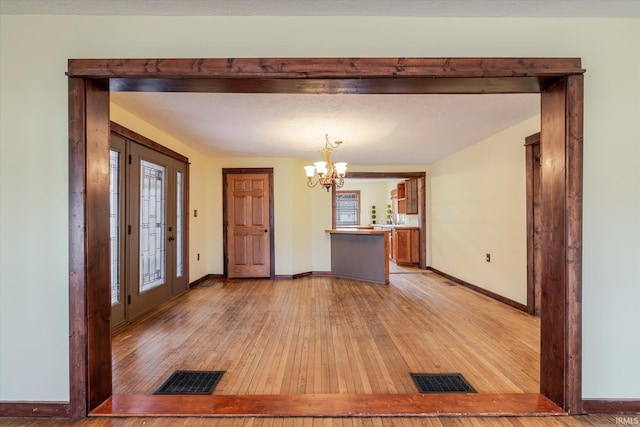 entryway featuring an inviting chandelier, light wood-style flooring, visible vents, and baseboards