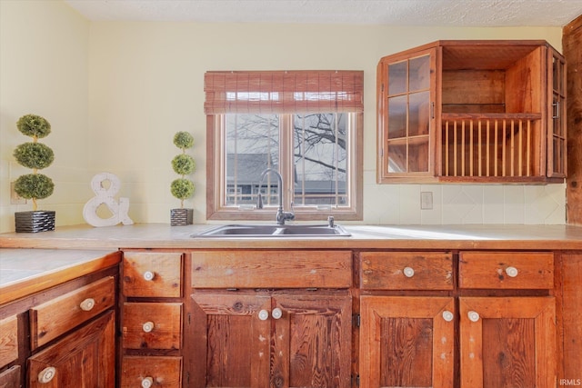 kitchen with tasteful backsplash, brown cabinets, light countertops, and a sink