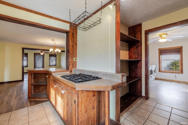 kitchen with washer and clothes dryer, open shelves, black gas cooktop, light countertops, and hanging light fixtures