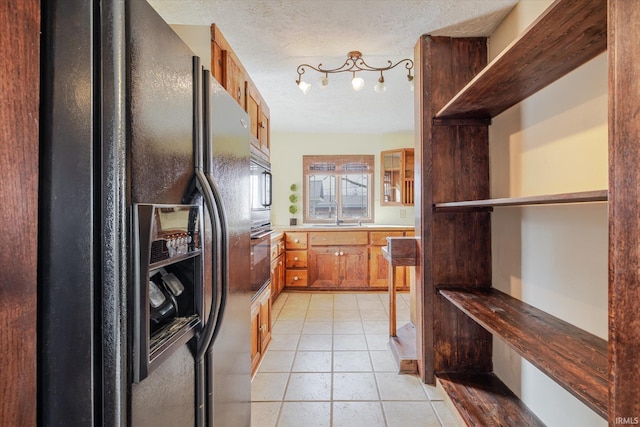 kitchen featuring a textured ceiling, light tile patterned flooring, black fridge with ice dispenser, brown cabinets, and glass insert cabinets