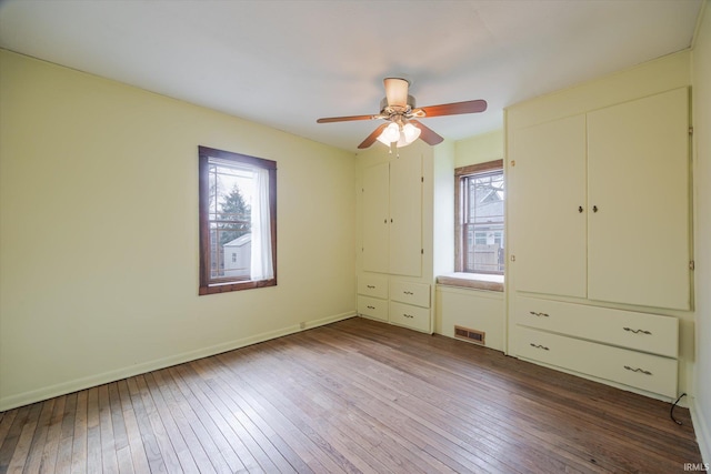 unfurnished bedroom with ceiling fan, hardwood / wood-style floors, visible vents, and baseboards