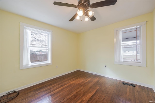 empty room featuring dark wood-style floors, visible vents, baseboards, and ceiling fan